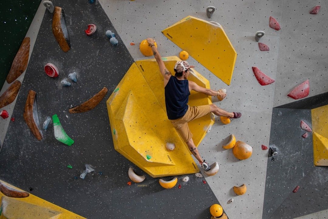 Klatrer bevæger sig på en indendørs bouldervæg over madrassen