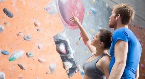 To klatrere studerer grebene på en indendørs bouldervæg